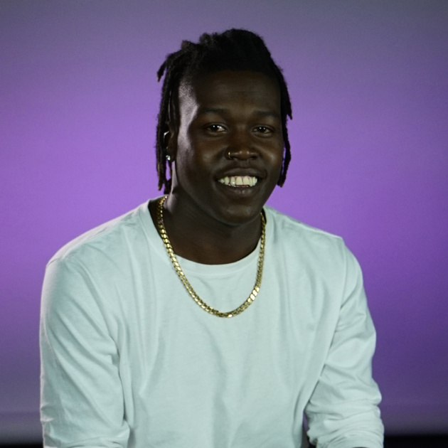 Student sitting and smiling in front of purple background