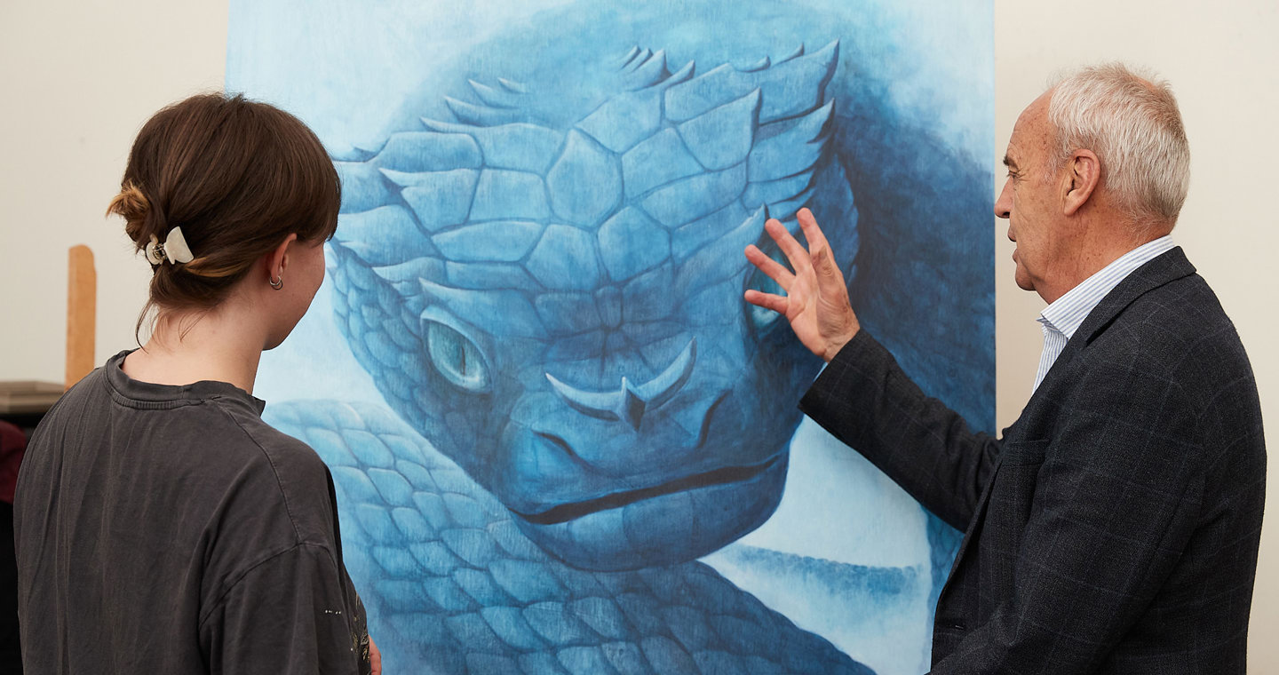 A Bachelor of Illustration teacher Stephen Pascoe and a student discussing the student's illustration, which is a large blue illustration.